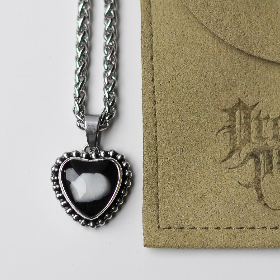 Heart-shaped pendant necklace with tooth on black background